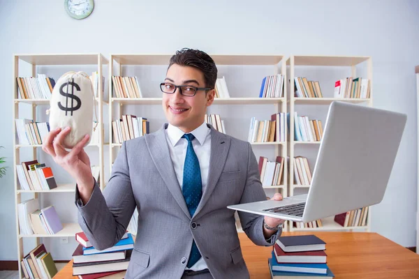 Empresário na biblioteca com um saco de dinheiro e um laptop — Fotografia de Stock