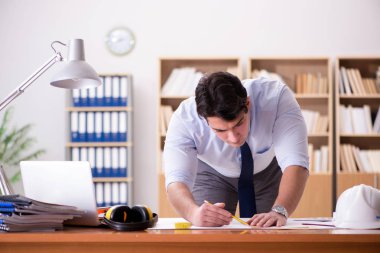 Ofiste çizimler üzerinde çalışan bir mühendis.