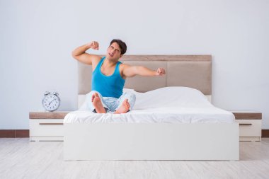 Genç adam yatakta uyanıyor.