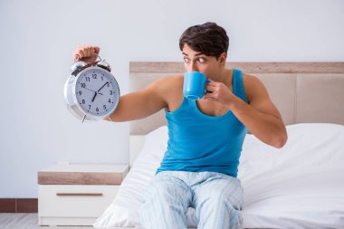 Genç adam yatakta uyanıyor.