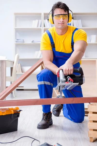 Reparador carpintero cortando aserrar una tabla de madera con un circuito — Foto de Stock