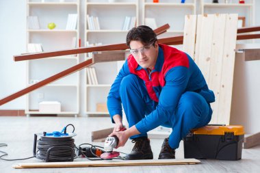 Genç marangoz ahşap kalaslarla çalışıyor.