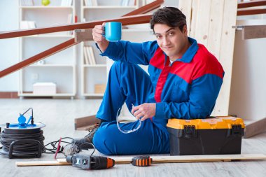 Genç marangoz ahşap kalaslarla çalışmaya ara veriyor.