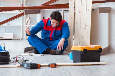 İnşaatta defter planlama yapan genç bir marangoz.