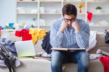 Genç adam dağınık bir odada çalışıyor.