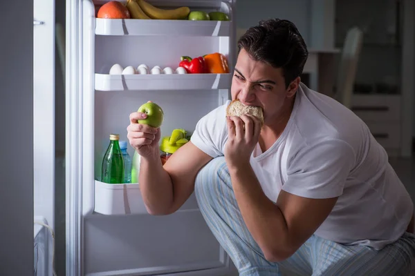 Homem na geladeira comendo à noite — Fotografia de Stock