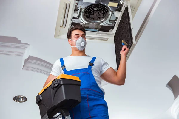 Worker repairing ceiling air conditioning unit