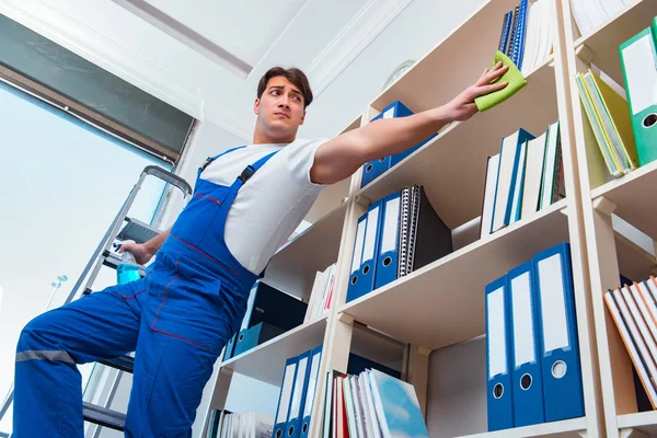 Male office cleaner cleaning shelves in office