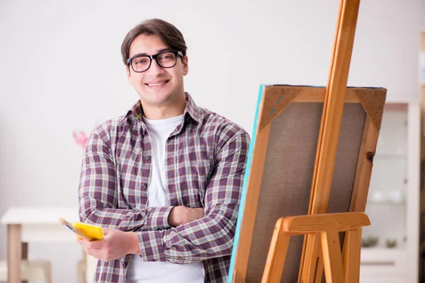 Νεαρός αρσενικός καλλιτέχνης ζωγραφίζει σε φωτεινό στούντιο — Φωτογραφία Αρχείου