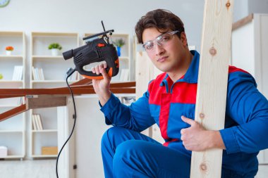 Genç marangoz ahşap kalaslarla çalışıyor.