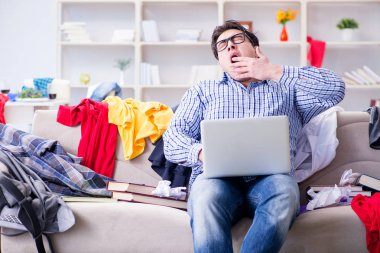 Genç adam dağınık bir odada çalışıyor.