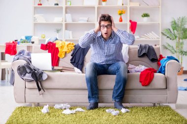 Genç adam dağınık bir odada çalışıyor.