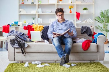 Genç adam dağınık bir odada çalışıyor.