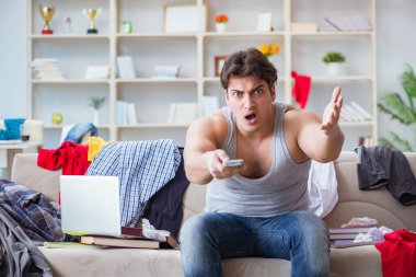 Genç adam dağınık bir odada çalışıyor.