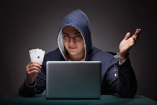 Giovane uomo in manette che indossa una felpa con cappuccio seduto di fronte a un la — Foto Stock