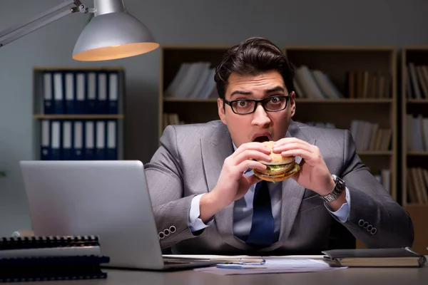 Empresario tarde en la noche comiendo una hamburguesa — Foto de Stock