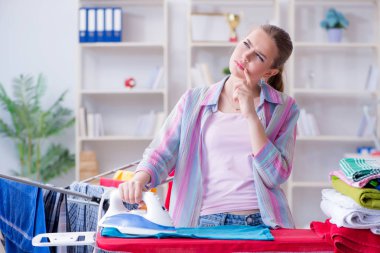 Üzücü kadın evde kıyafetleri ütülüyor.