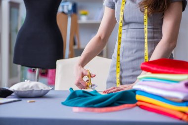 Kadın terzi dikiş dikmek için dikiş dikiyor.