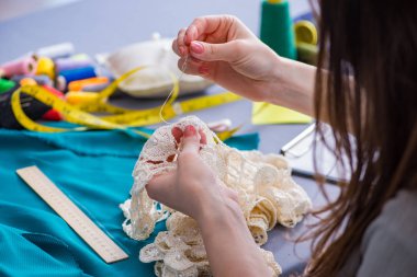 Kadın terzi dikiş dikmek için dikiş dikiyor.