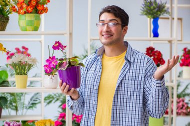 Çiçekçide çalışan genç bir adam.