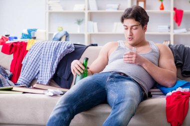 Dağınık bir odada alkol alan genç bir öğrenci.