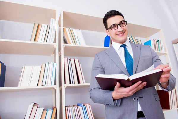 İşadamı öğrenci kütüphanede bir kitap okuyor.