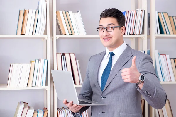 Kütüphanede çalışan bilgisayarlı bir iş adamı.