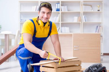 Tamirci marangoz ahşap bir tahtayı kesiyor.