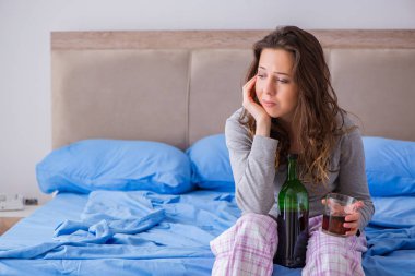 Evde alkol alan genç bir kadın depresyonda.