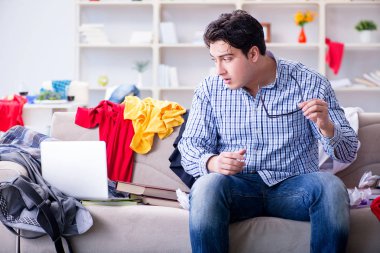 Genç adam dağınık bir odada çalışıyor.