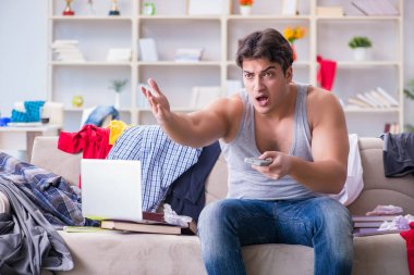 Genç adam dağınık bir odada çalışıyor.