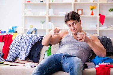 Dağınık bir odada alkol alan genç bir öğrenci.