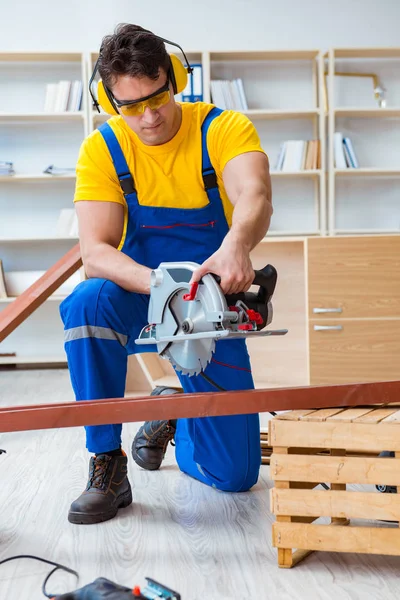 Reparador carpintero cortando aserrar una tabla de madera con un circuito — Foto de Stock