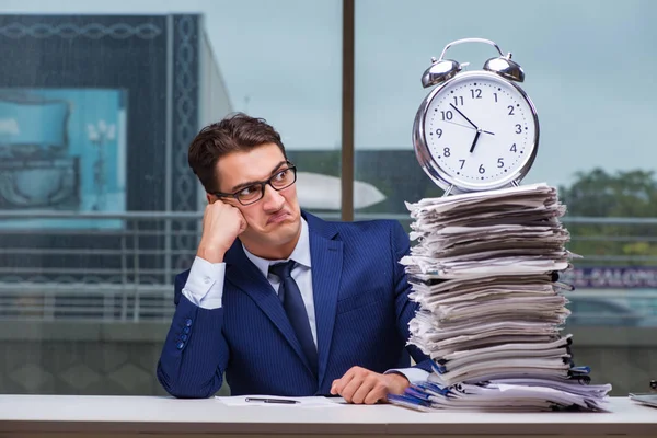 Yığınla evrak işi ve alarm sistemi olan bir iş adamı.