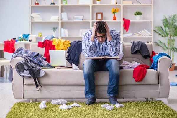 Genç adam dağınık bir odada çalışıyor.