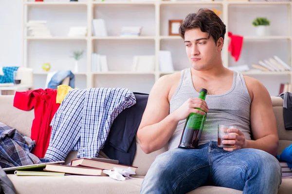 Молодой человек пьет алкоголь в грязной комнате — стоковое фото