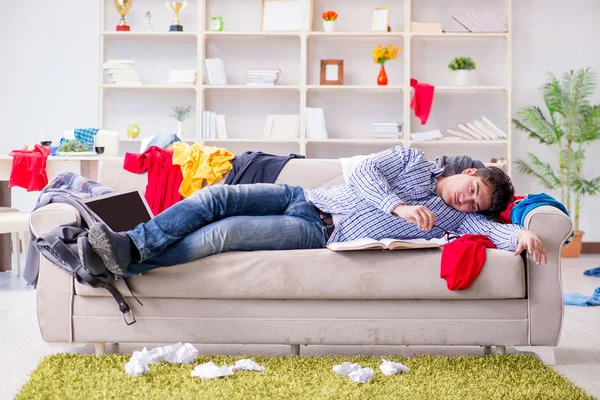 Genç adam dağınık bir odada çalışıyor.