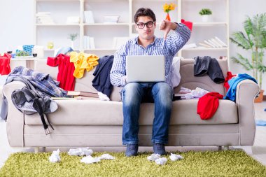 Genç adam dağınık bir odada çalışıyor.