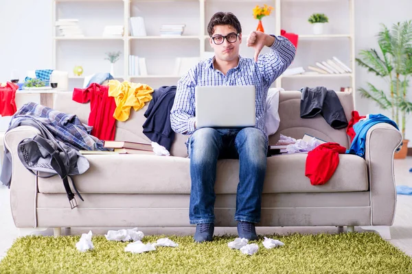 Genç adam dağınık bir odada çalışıyor.