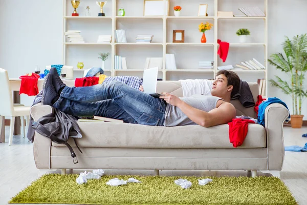 Genç adam dağınık bir odada çalışıyor.