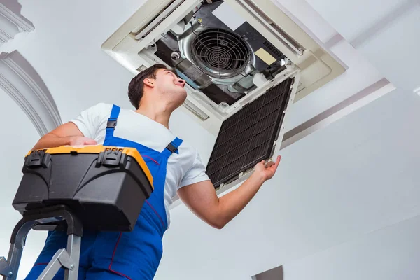 Worker repairing ceiling air conditioning unit — Stock Photo, Image