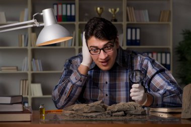 Arkeolog geç saatlere kadar ofiste çalışıyor.