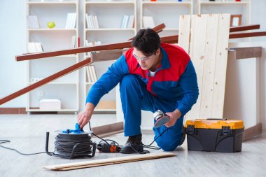 Genç marangoz ahşap kalaslarla çalışıyor.