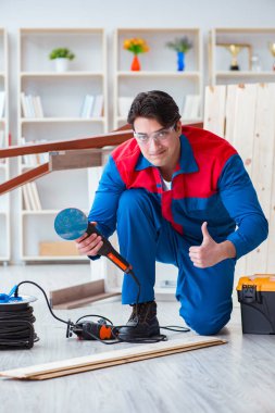 Genç marangoz ahşap kalaslarla çalışıyor.