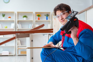 Genç marangoz ahşap kalaslarla çalışıyor.