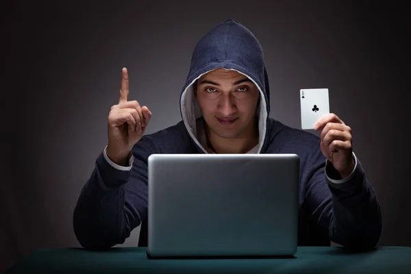 Jovem usando um capuz sentado na frente de um computador portátil — Fotografia de Stock