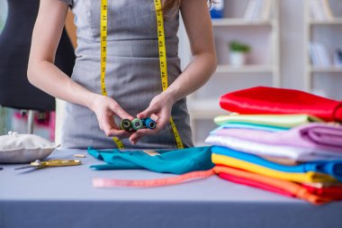 Kadın terzi dikiş dikmek için dikiş dikiyor.