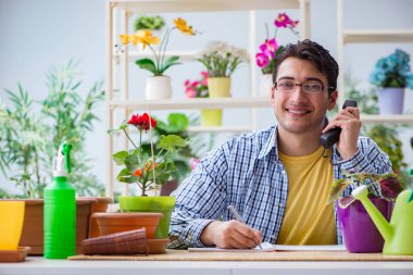 Çiçekçide çalışan genç bir adam.