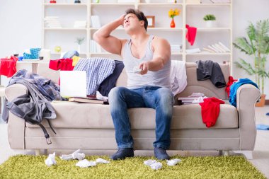 Genç adam dağınık bir odada çalışıyor.