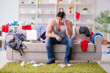 Genç adam dağınık bir odada çalışıyor.